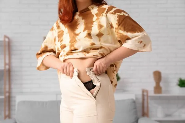 Image of woman trying to do her trousers up after pregnancy weight gain Blackpool