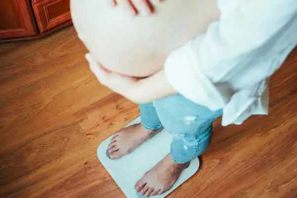 Image of woman weighing herself and experiencing weight gain through pregnancy Blackpool